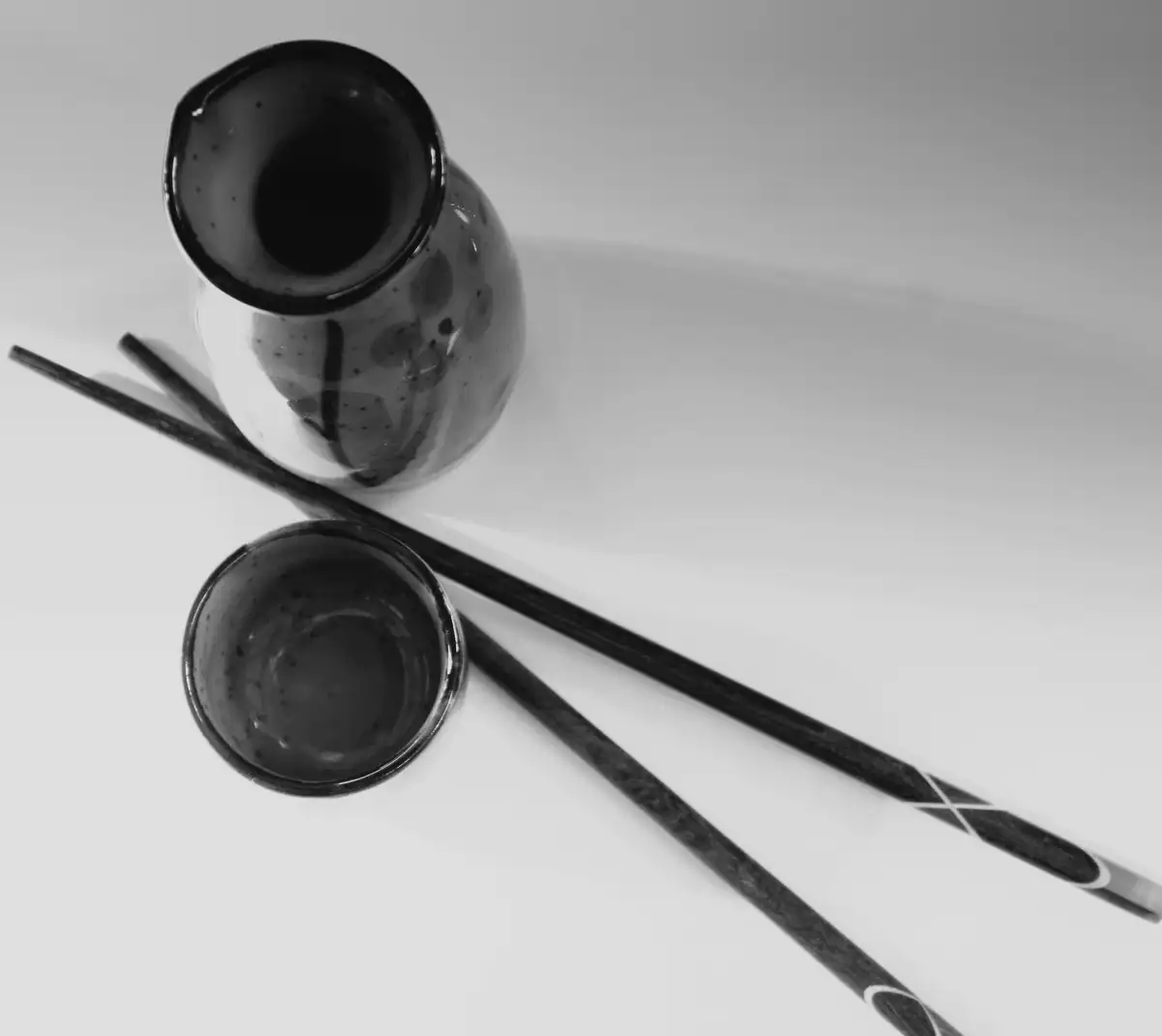 白い卓の上の、黒い器と二本の箸の白黒写真
